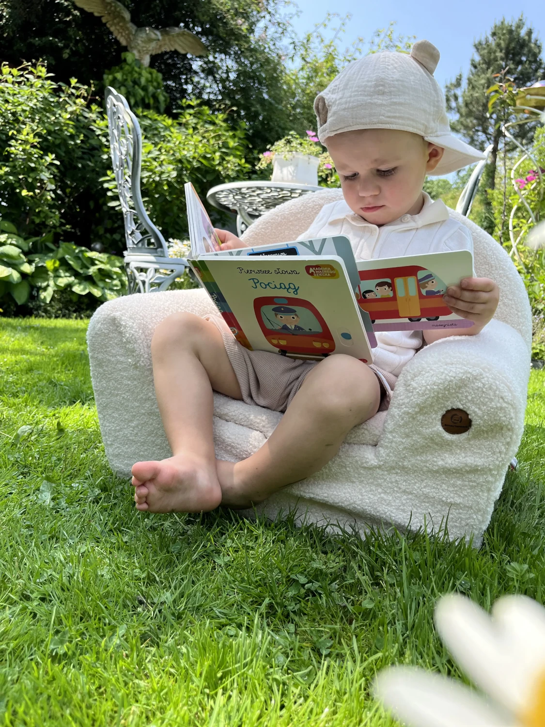Ein Kind liest ein Büchlein und sitzt auf dem Schaumstoffsessel BUBU